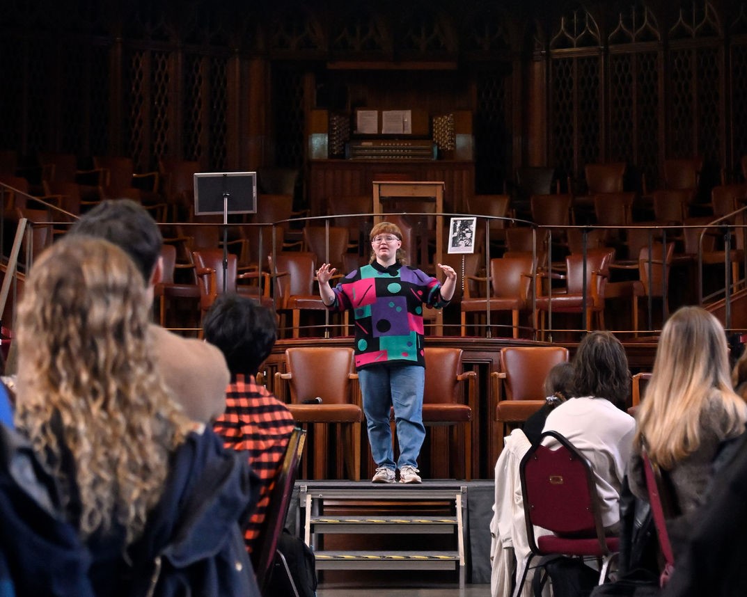 Student on raised stage presenting to large audience